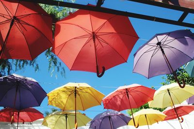 Low angle view of colorful umbrellas hanging against clear sky