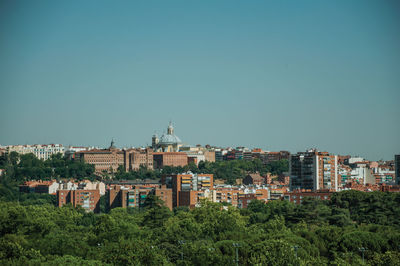 Buildings in city against clear blue sky