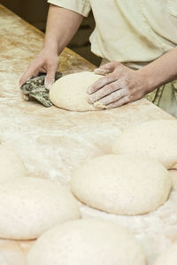 Baker preparing sourdough bread loaves on wooden work top