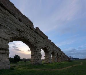 Low angle view of old ruins on field against sky