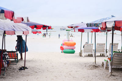 Lounge chairs and parasols at beach against sky