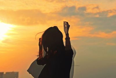 Multiple exposure of woman gesturing while standing against cloudy sky during sunset