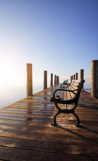 Empty chairs on wooden post against clear blue sky