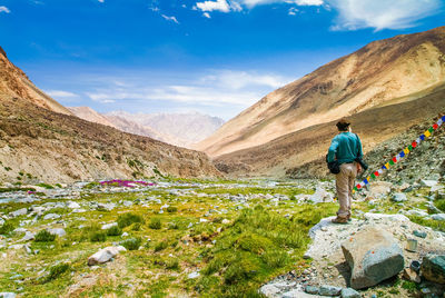 Rear view of man standing on rock against sky