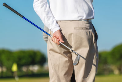 Midsection of man holding umbrella while standing outdoors