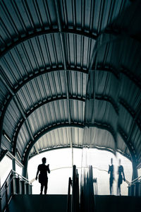 Silhouette of commuter at mass transit station, man holding phone and walking down stairs