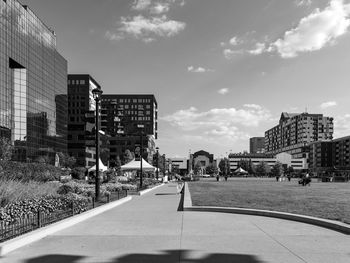 People on road by buildings against sky