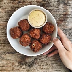 Cropped image of hand serving bitterballen in plate on table