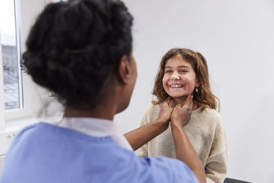 Female doctor examining girl patient's neck