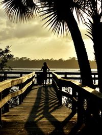 Silhouette man standing on pier over lake