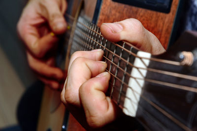 Midsection of man playing guitar indoors