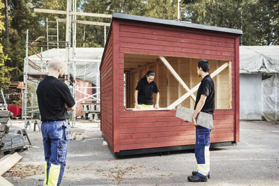 Teacher looking at carpentry students working on wooden cabin