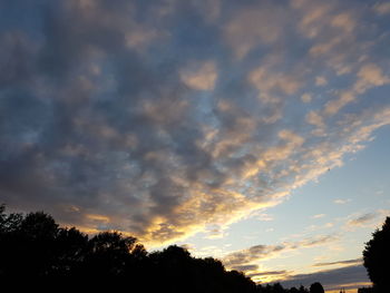 Low angle view of silhouette trees against dramatic sky