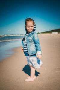 Full length portrait of cute girl standing at beach