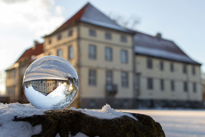 Close-up of snow covered with reflection of building in background