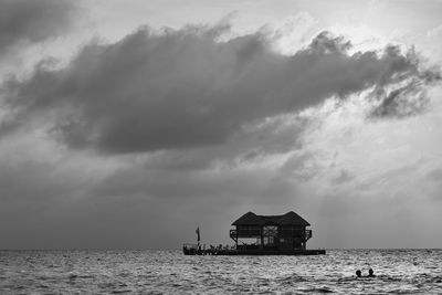 Silhouette built structure by sea against sky