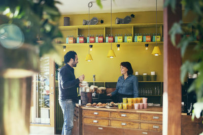 Smiling customer with waitress standing in coffee shop