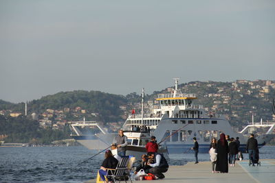 People on ship in sea against sky