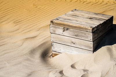 A close up shot of a single wooden box being consumed slowly by the sand in bolonia, spain