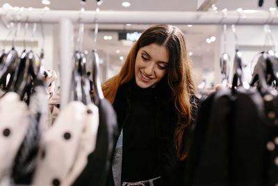 Happy young girl in a shop looking choosing and buying clothes