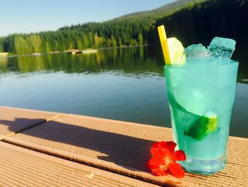 Close-up of drink on table by lake