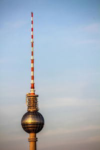 Communications tower in city against sky