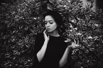 Young woman with eyes closed against plants