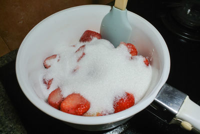 High angle view of strawberries with sugar in bowl on table