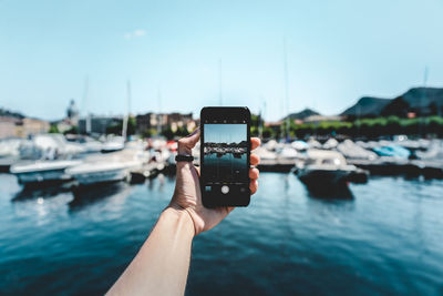 Close-up of hand holding camera against sea
