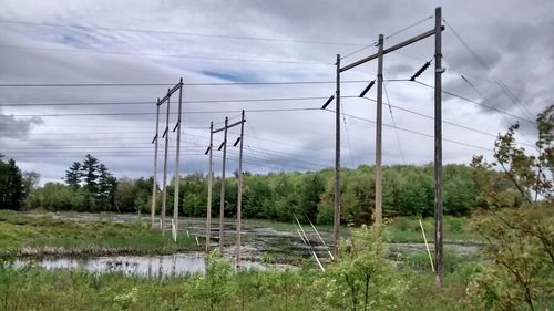 Electricity pylon on landscape against cloudy sky