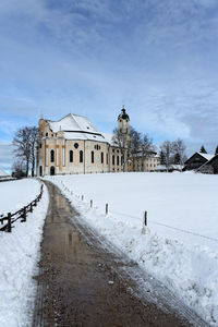 Empty road amidst snow covered field leading towards wies church at winter