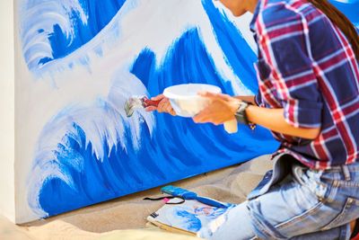 Talented female artist painting on wooden canvas working on modern abstract oil painting at festival