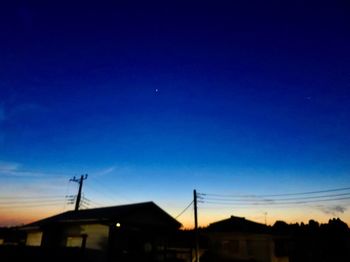 Silhouette buildings against blue sky at night