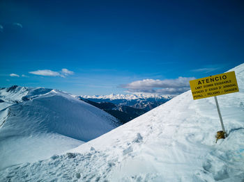 Text on snow covered mountain against blue sky