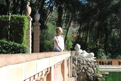 Woman sitting by statue against trees in spain