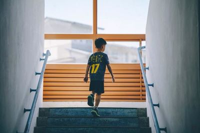 Rear view of boy running on staircase