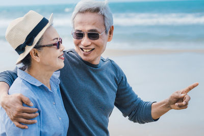 Happy friends with sunglasses against sea