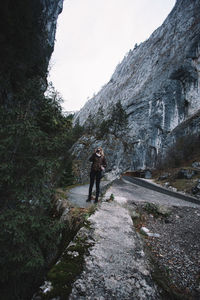Man walking on road by mountain against sky