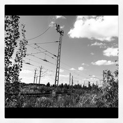Electricity pylon on field against cloudy sky