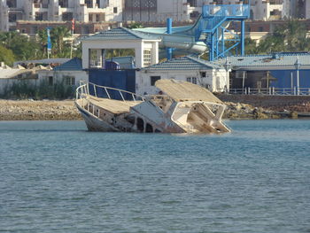 Boat moored on sea by buildings in city