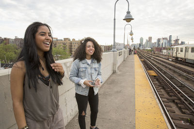 Happy young woman standing on railroad tracks in city