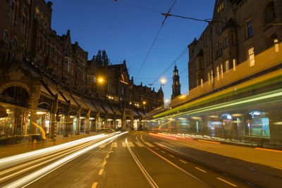 Light trails on city street amidst historic buildings at night