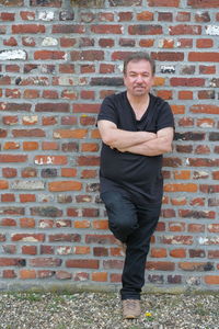 Low section of man standing against brick wall