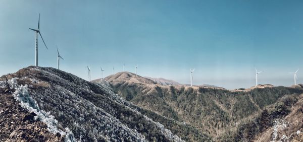 Panoramic view of wind turbines on landscape against sky