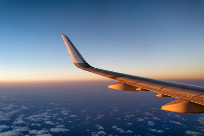 Airplane flying over sea against sky during sunset