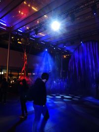 People walking on illuminated stage in city at night