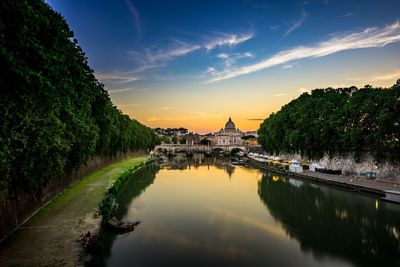 View of river amidst historical buildings against sky during sunset