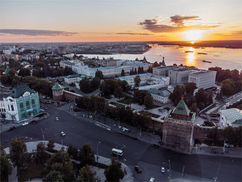 High angle view of buildings by sea against sky during sunset