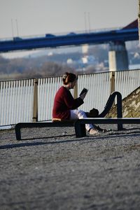 Man sitting on bench against sky