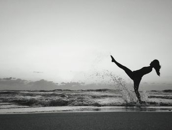 Silhouette of woman jumping on beach